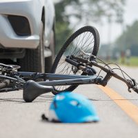 aftermath of car accident with cyclist with helmet and bicycle in view