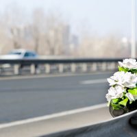 Artificial white roses flowers on the site of a car crash traffic accident on the bridge safety metal fence with a fatal outcome with vehicle movement
